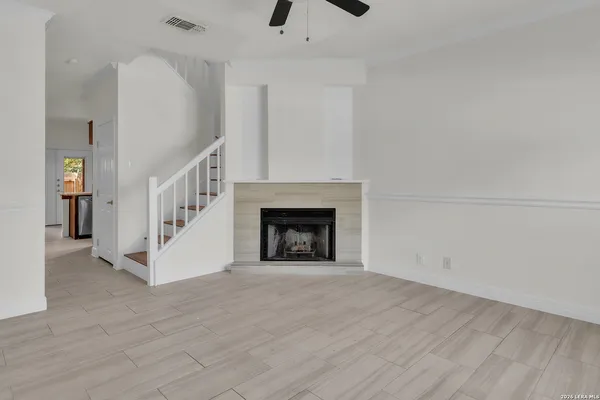 a view of an empty room with wooden floor and a fireplace