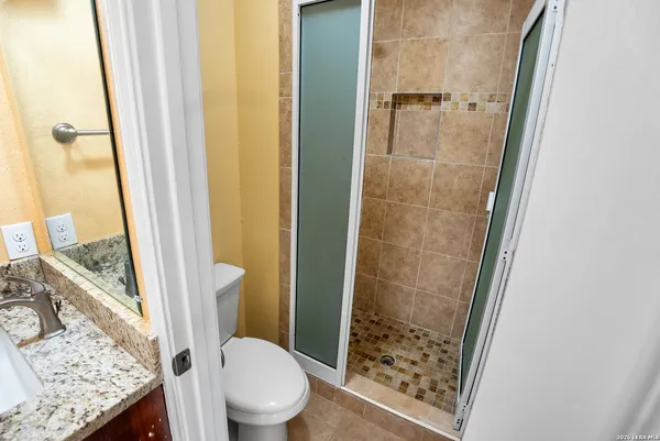 a bathroom with a granite countertop shower and a toilet