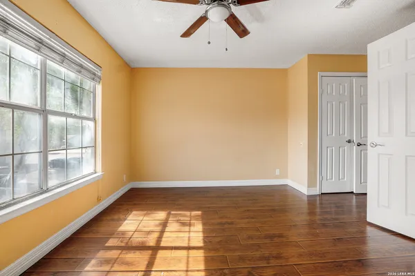 a view of empty room with wooden floor and fan