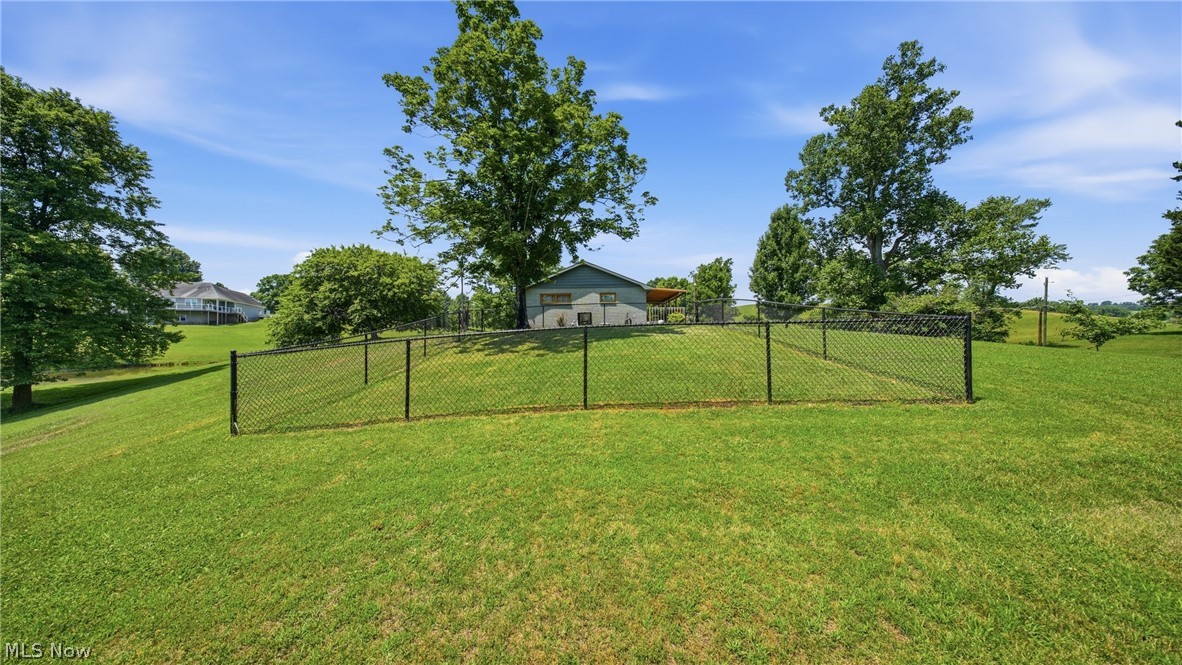 89 Dagg Road Parkersburg, WV 26101 - Photo 8 of 45 Expansive green lawn with a black chain-link fence enclosing a portion of the property