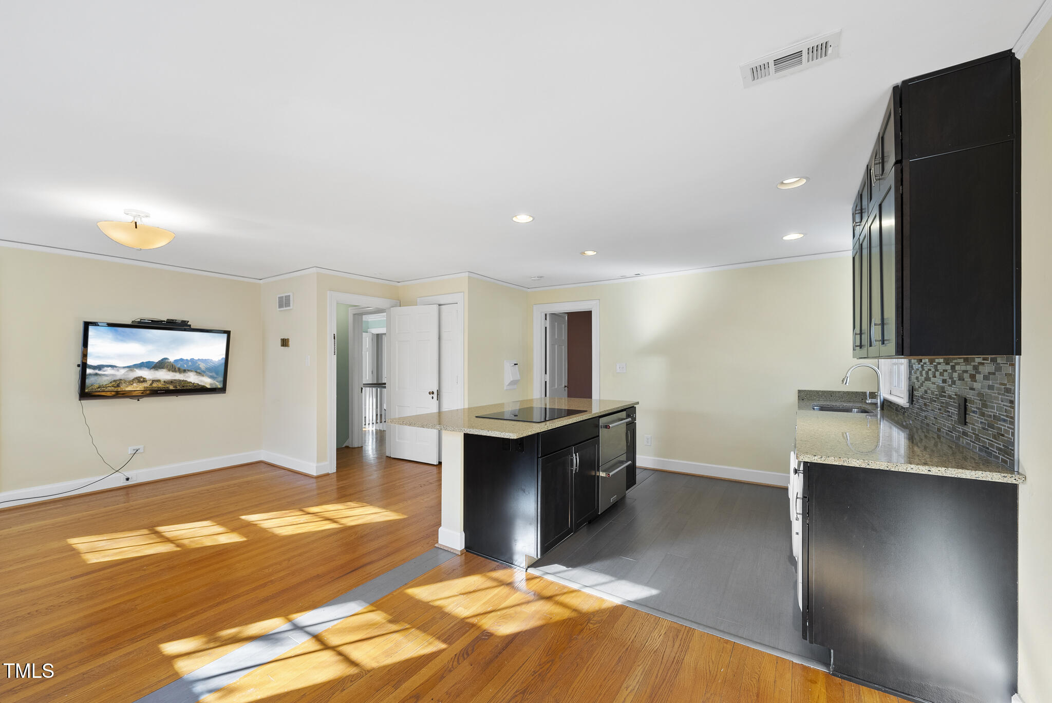 23 Shepherd Street Raleigh, NC 27607 - Photo 18 of 36 a view of a kitchen with kitchen island a sink wooden floor and a living room