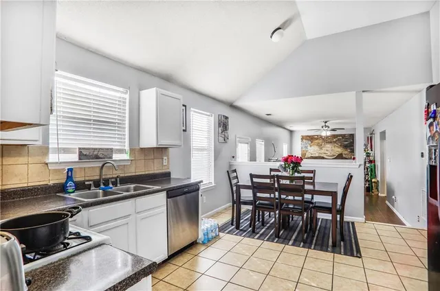 a kitchen with stainless steel appliances kitchen island granite countertop a table chairs and a refrigerator