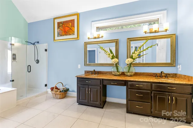 a spacious bathroom with a granite countertop double vanity sink a mirror and a bathtub