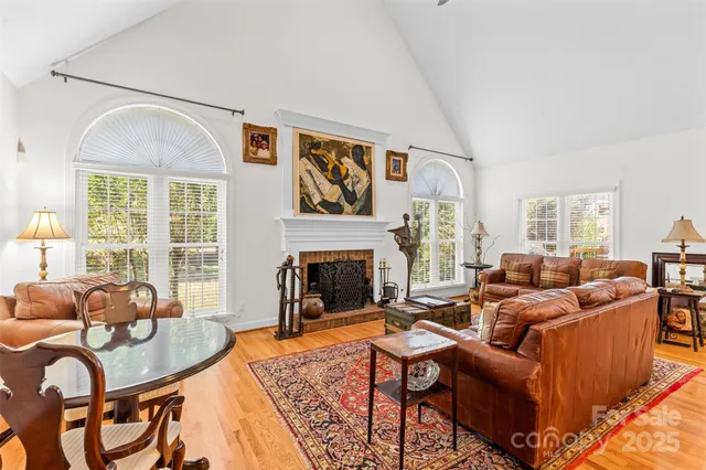 a living room with furniture a fireplace and large windows