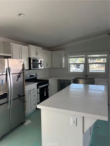 a kitchen with kitchen island a counter top space a sink and appliances