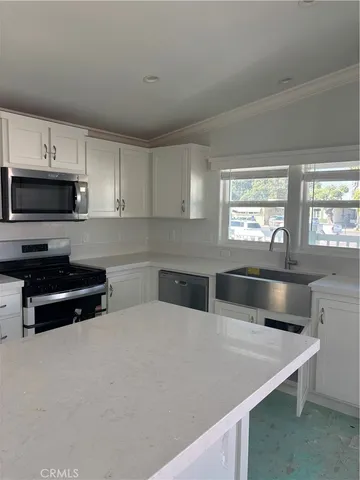 a kitchen with stainless steel appliances a stove a sink a microwave a stove and white cabinets