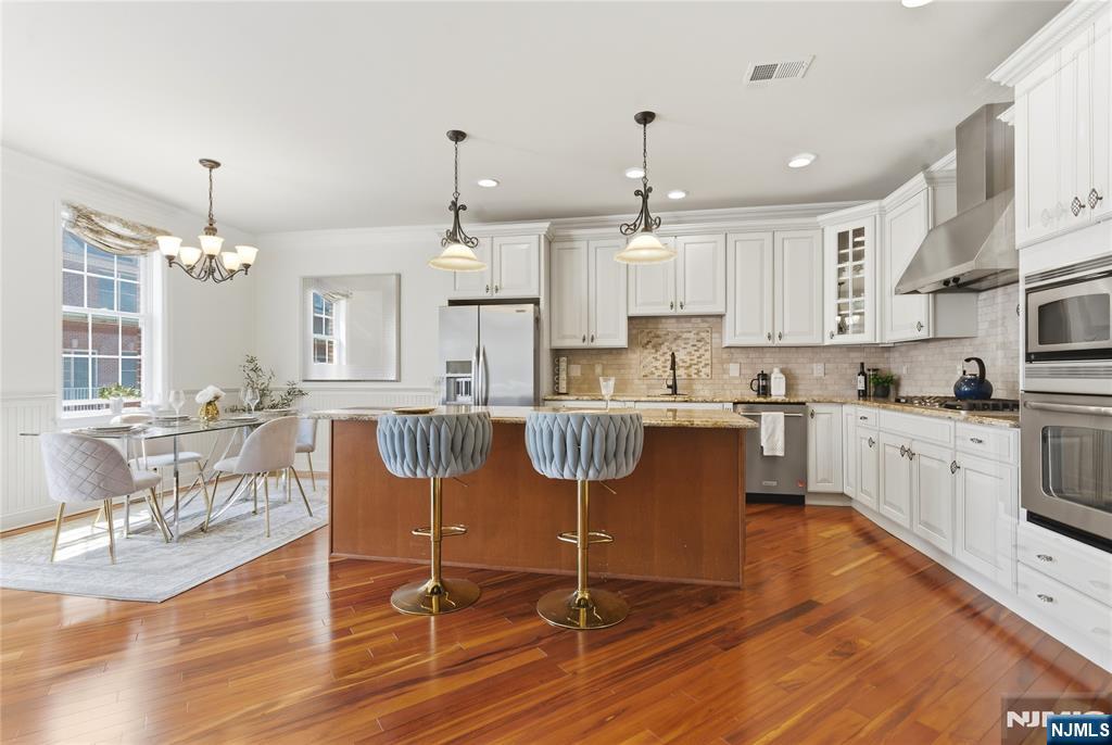 14 Gable Walk Livingston, NJ 07039 - Photo 12 of 41 a kitchen with stainless steel appliances granite countertop a stove top oven a refrigerator a dining table and chairs with wooden floor