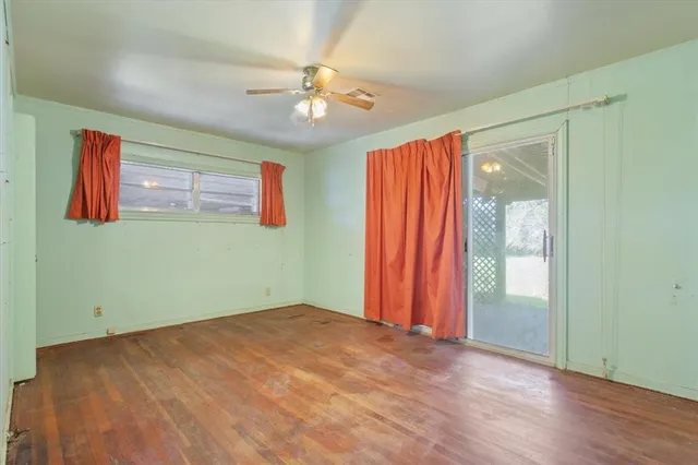 a view of an empty room with window and hardwood floor