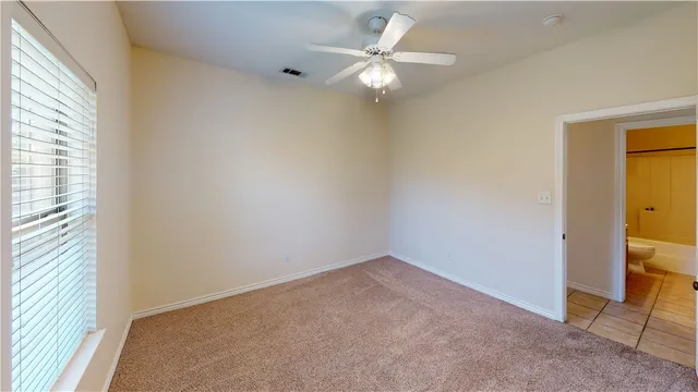 an empty room with a window and a ceiling fan