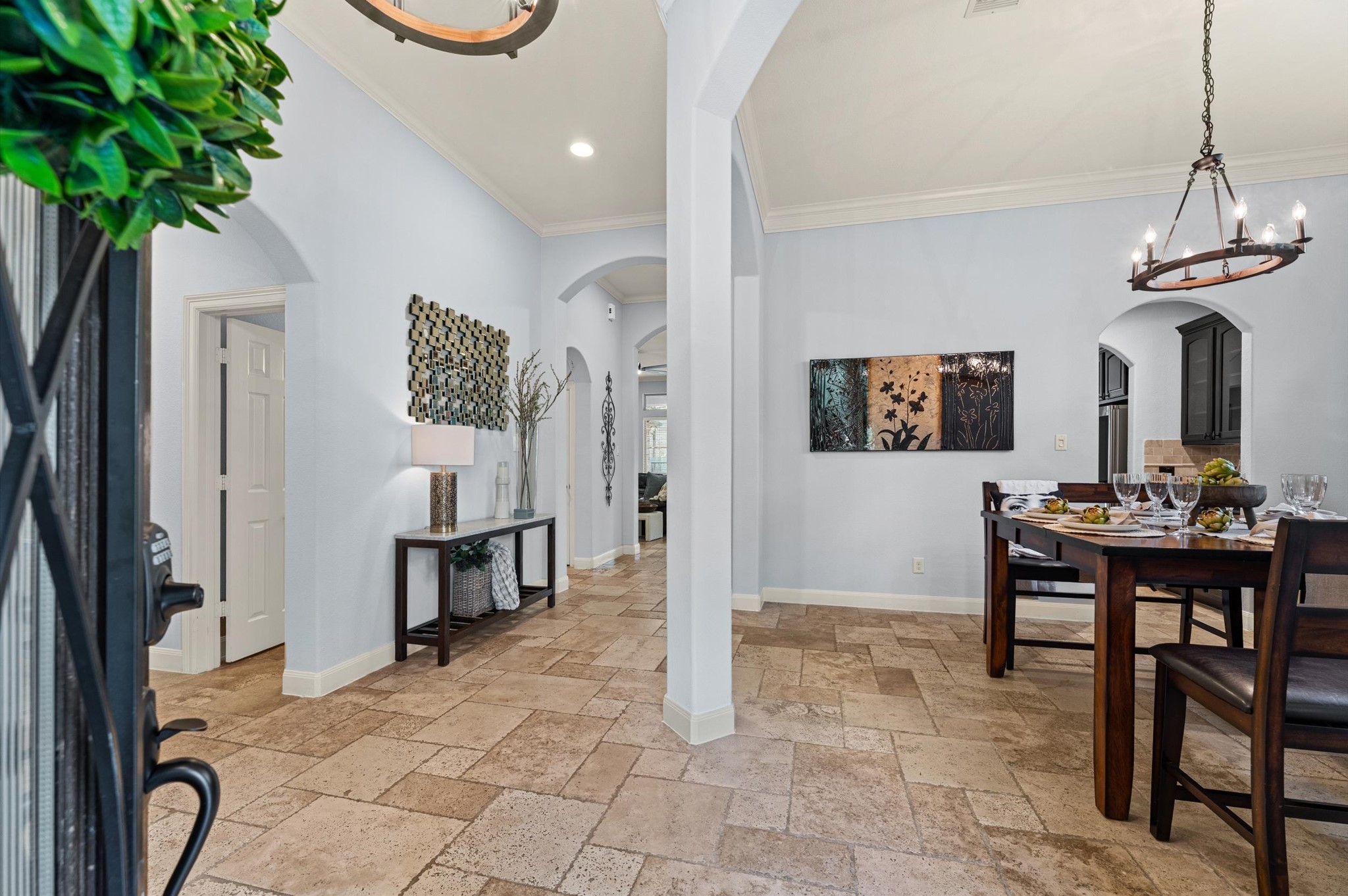 70 Valera Ridge Drive Spring, TX 77389 - Photo 9 of 37 This inviting home features an elegant dining area with a stylish chandelier and a beautifully decorated hallway. The space has light-colored walls, a mix of tile flooring, and tasteful artwork, creating a warm and welcoming atmosphere.