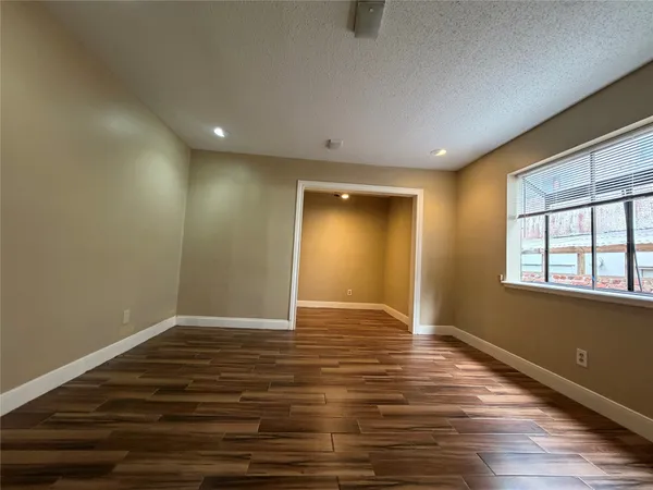 a view of an empty room with window and wooden floor