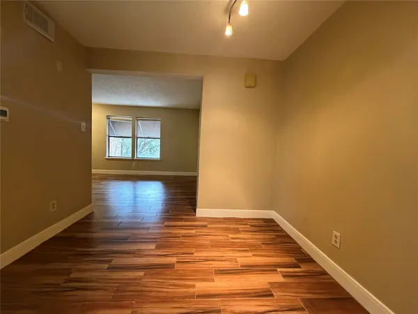 a view of empty room with wooden floor and fan