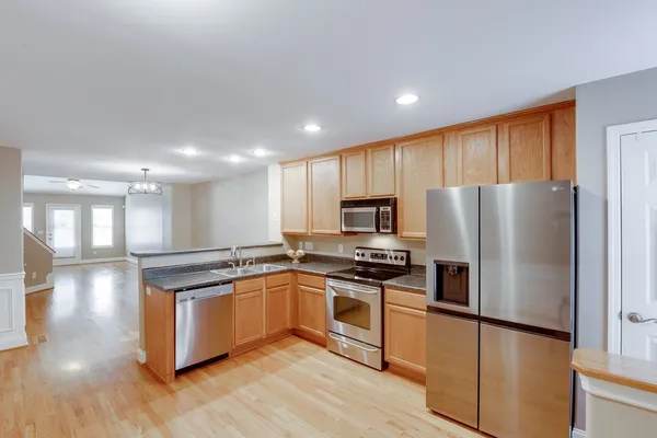 a kitchen with stainless steel appliances granite countertop a stove a refrigerator a sink a oven with wooden floor and cabinets