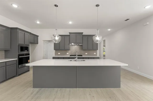 a large kitchen with kitchen island a sink stainless steel appliances and a counter top