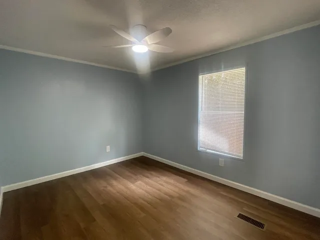 an empty room with wooden floor and windows