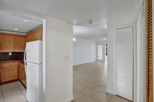 a view of a refrigerator in kitchen and an empty room
