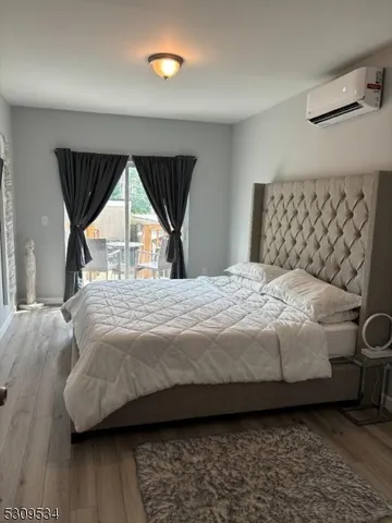 a bedroom with a bed next to a window with a wooden floor