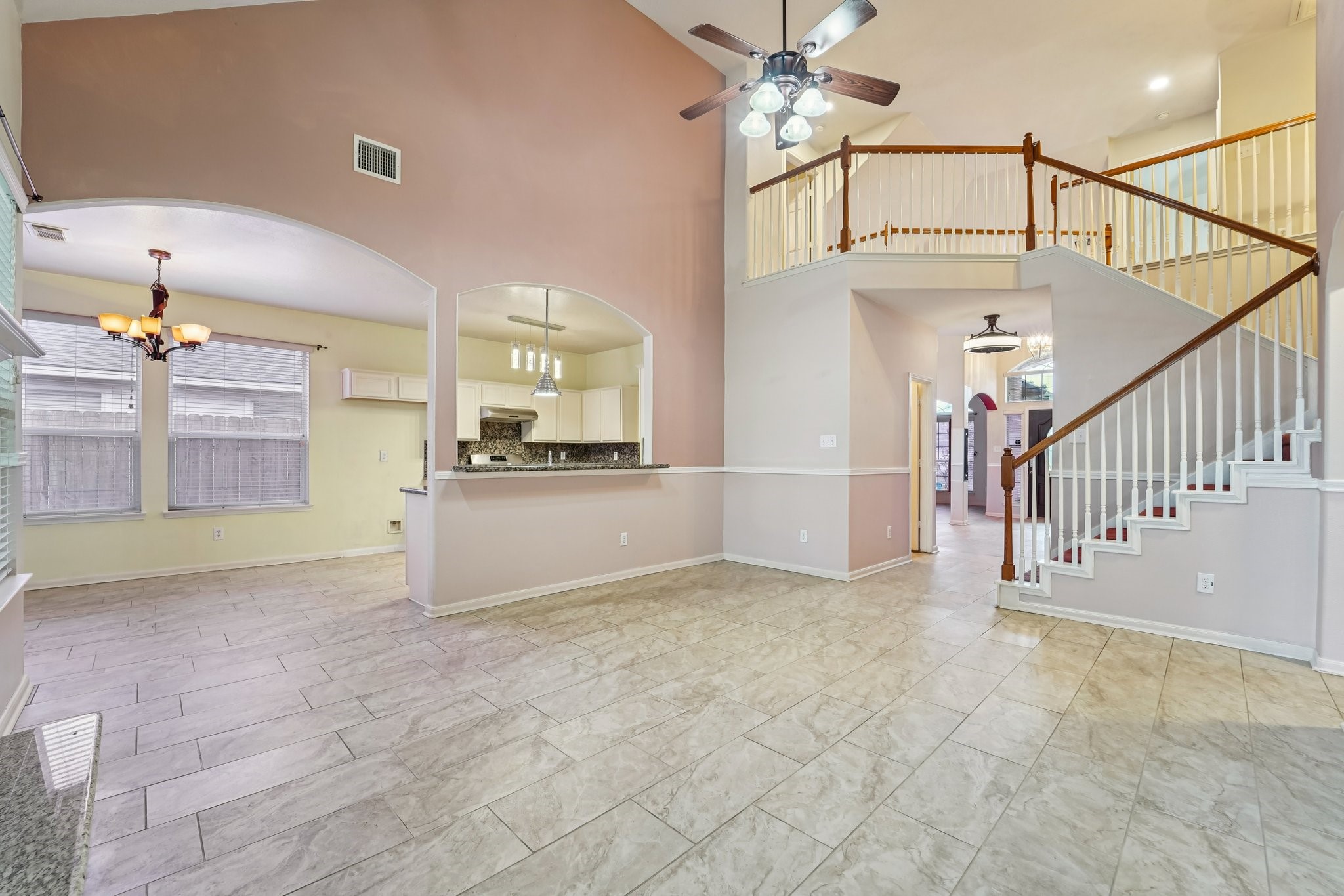 3818 Ridge Canyon Road Baytown, TX 77521 - Photo 15 of 42 This spacious living area features high ceilings, tile flooring, and an open layout. It includes a modern kitchen with granite countertops, a dining area, and a stylish staircase leading to the upper level. Natural light fills the space through large windows, complementing the contemporary lighting fixtures.