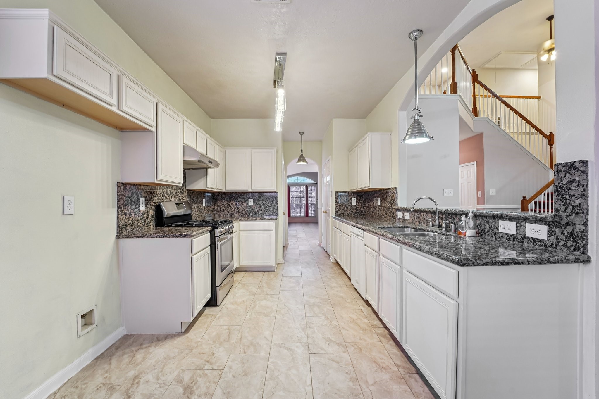 3818 Ridge Canyon Road Baytown, TX 77521 - Photo 16 of 42 This spacious kitchen features granite countertops, white cabinetry, and stainless steel appliances. It boasts a modern open layout with a view of the dining area and an adjacent staircase, enhancing the home's flow and functionality.