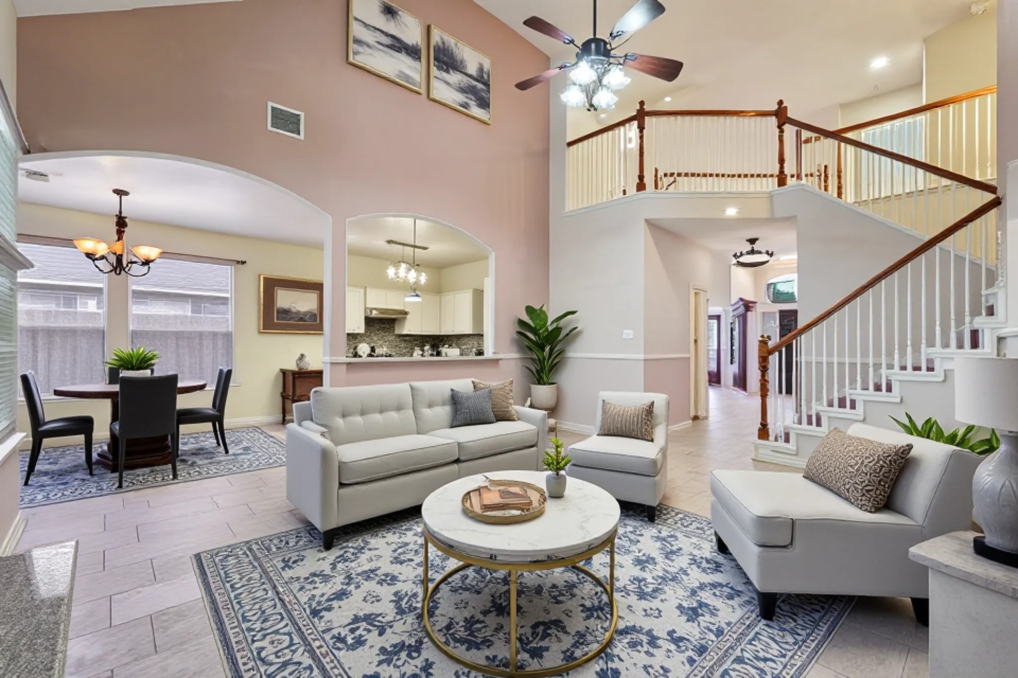 3818 Ridge Canyon Road Baytown, TX 77521 - Photo 2 of 42 This spacious living area features high ceilings, tile flooring, and an open layout. It includes a modern kitchen with granite countertops, a dining area, and a stylish staircase leading to the upper level. Natural light fills the space through large windows, complementing the contemporary lighting fixtures.