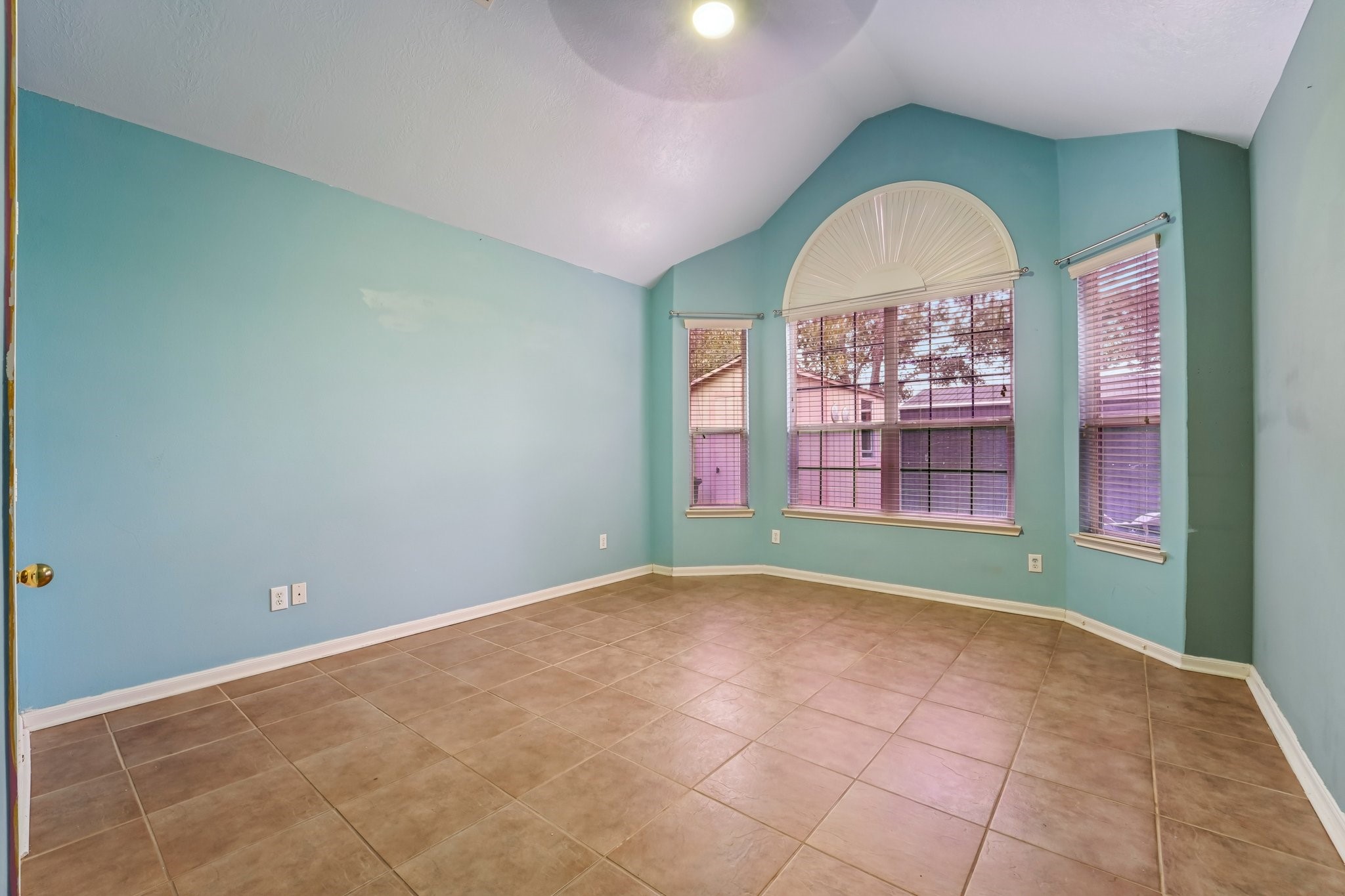 3818 Ridge Canyon Road Baytown, TX 77521 - Photo 23 of 42 Bright, spacious room with vaulted ceiling, large windows, and tiled flooring, perfect for ample natural light. Walls are painted in a soothing blue, enhancing the airy feel. Ideal for a bedroom or home office.
