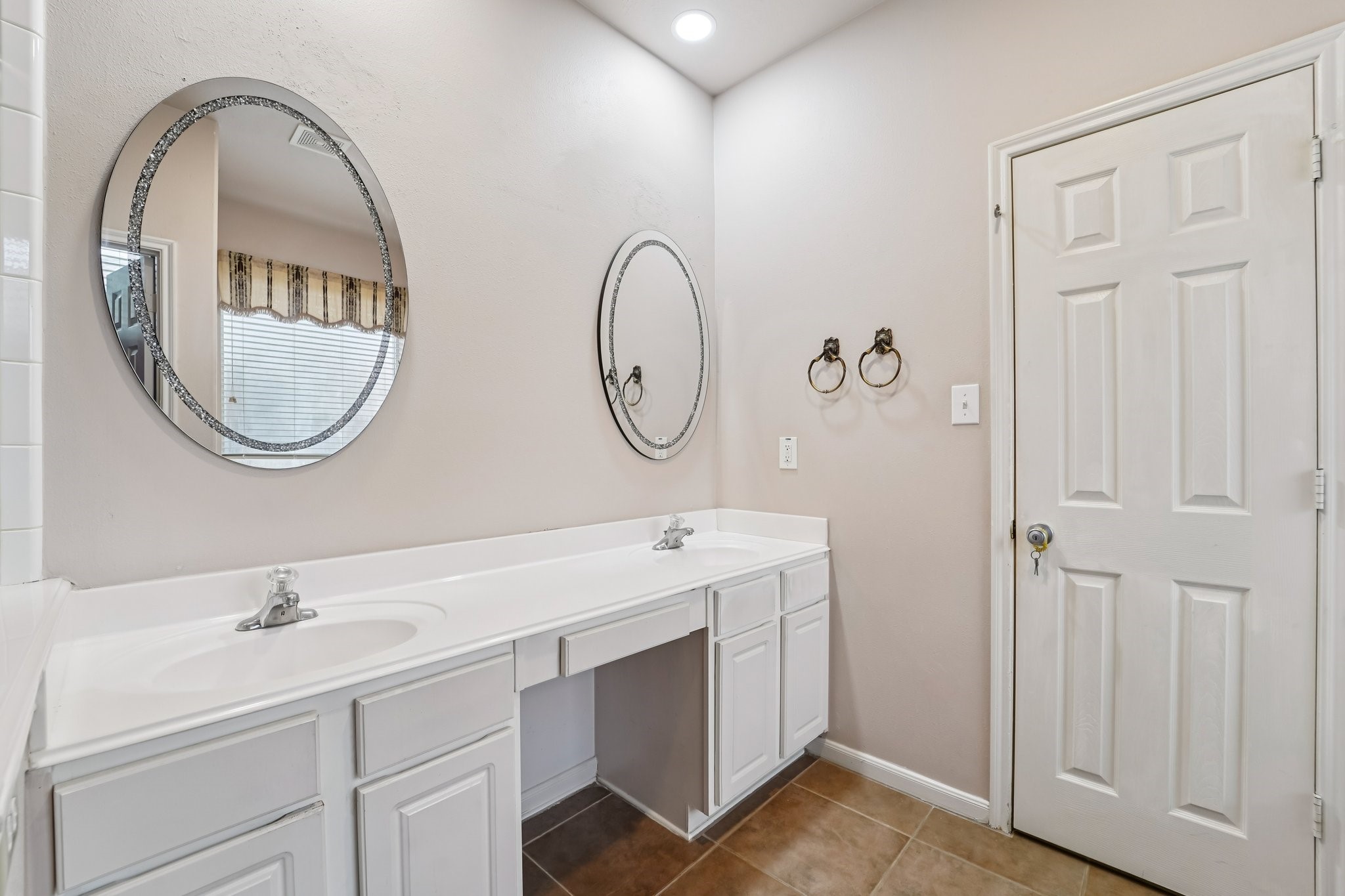 3818 Ridge Canyon Road Baytown, TX 77521 - Photo 27 of 42 This bathroom features a dual-sink vanity with a clean white countertop and cabinetry, complemented by two round mirrors. The neutral walls and recessed lighting create a bright, welcoming space.