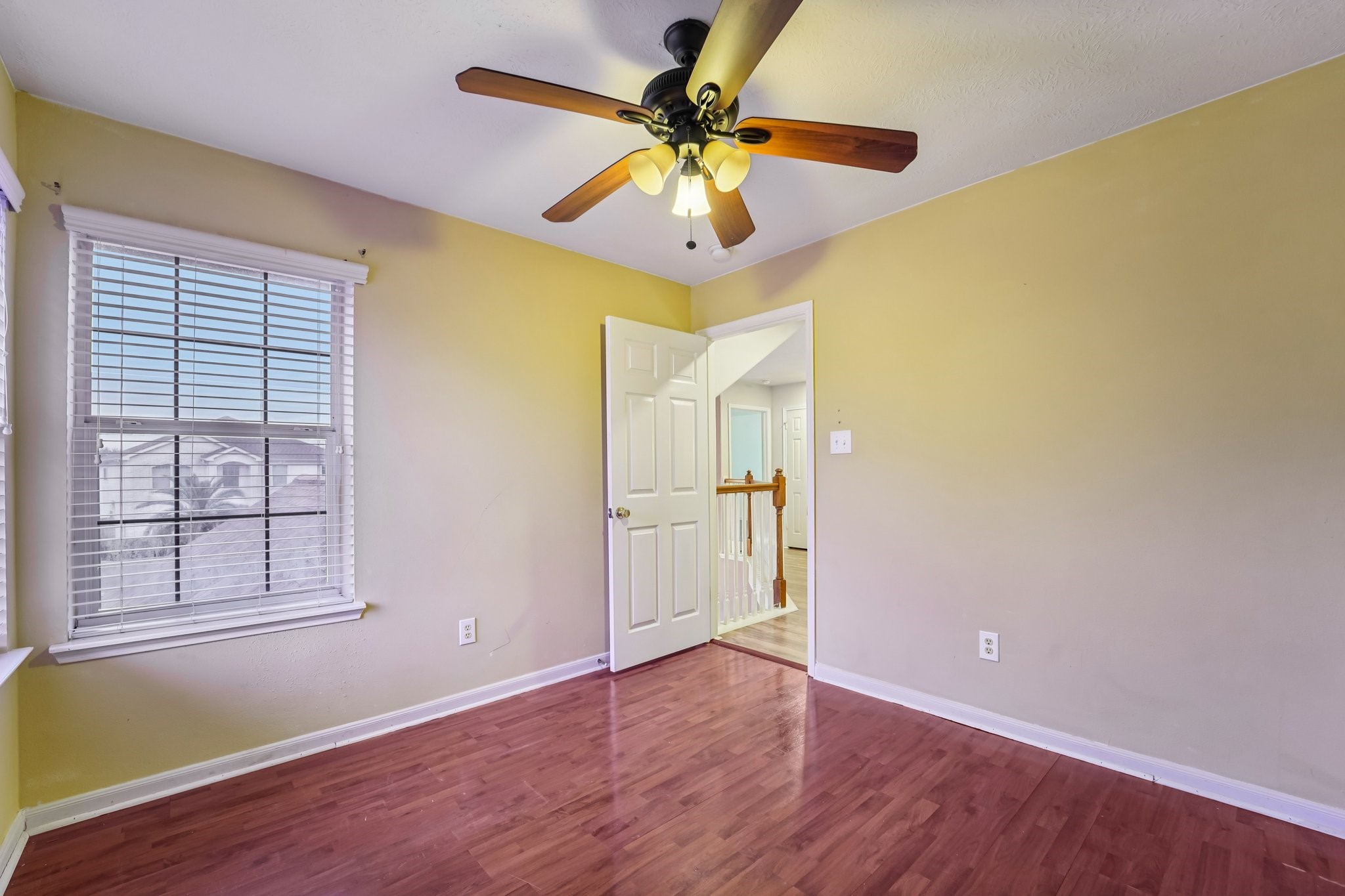 3818 Ridge Canyon Road Baytown, TX 77521 - Photo 32 of 42 This room features warm yellow walls, hardwood floors, and a ceiling fan. It has a window with blinds for natural light and an open door leading to a hallway.