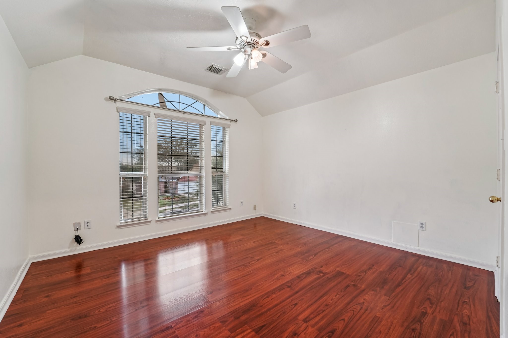 3818 Ridge Canyon Road Baytown, TX 77521 - Photo 34 of 42 This room features rich hardwood flooring and high ceilings, enhanced by a large arched window that allows plenty of natural light. It includes a ceiling fan for added comfort, making it a bright and welcoming space.