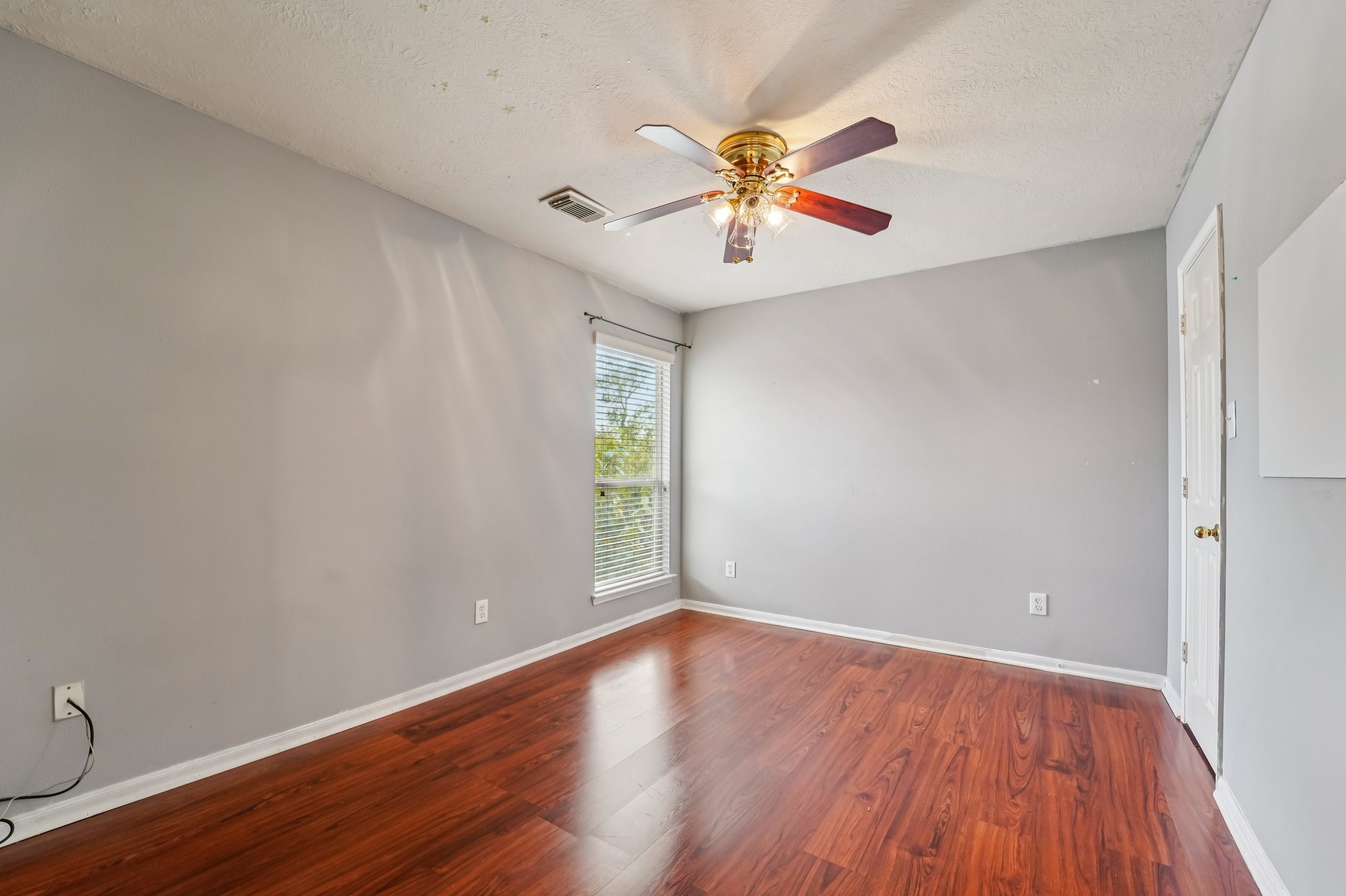 3818 Ridge Canyon Road Baytown, TX 77521 - Photo 35 of 42 This room features fresh gray walls, rich hardwood floors, and a ceiling fan with lights. A large window brings in natural light, making it a bright and inviting space.