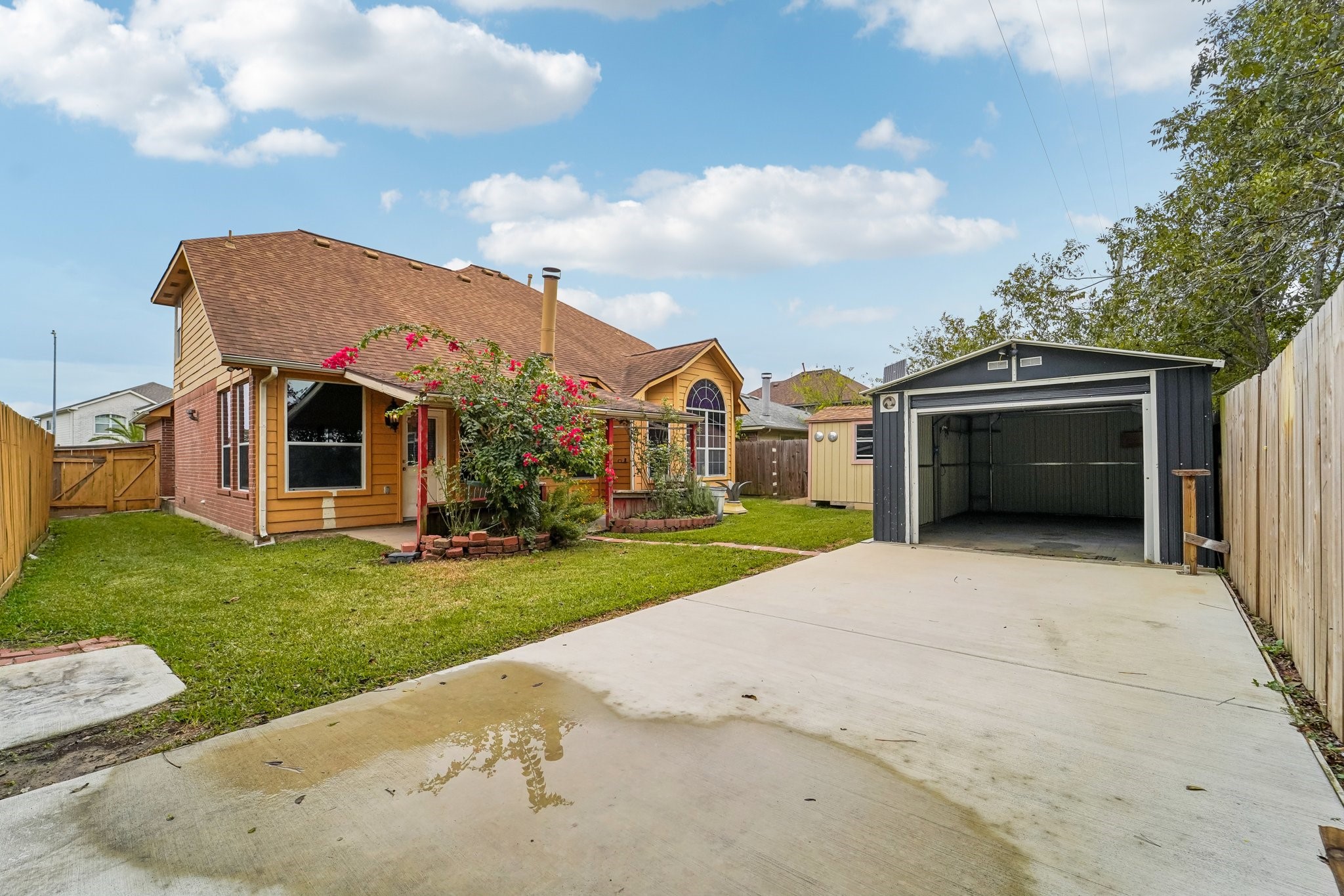 3818 Ridge Canyon Road Baytown, TX 77521 - Photo 41 of 42 Charming home with a spacious backyard, featuring a well-maintained lawn, a detached garage, and a cozy garden area with flowering plants. Ideal for outdoor activities and storage.