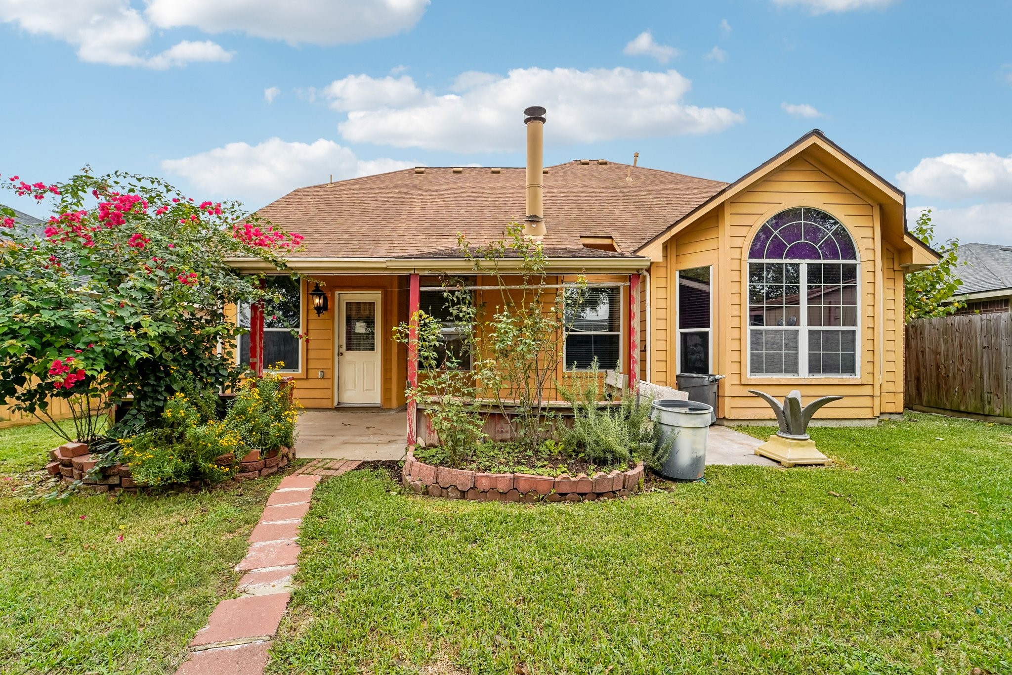 3818 Ridge Canyon Road Baytown, TX 77521 - Photo 6 of 42 Charming home with a warm yellow exterior, featuring a well-maintained garden and a spacious backyard. The large arched window adds character and invites natural light. Perfect for enjoying outdoor living.