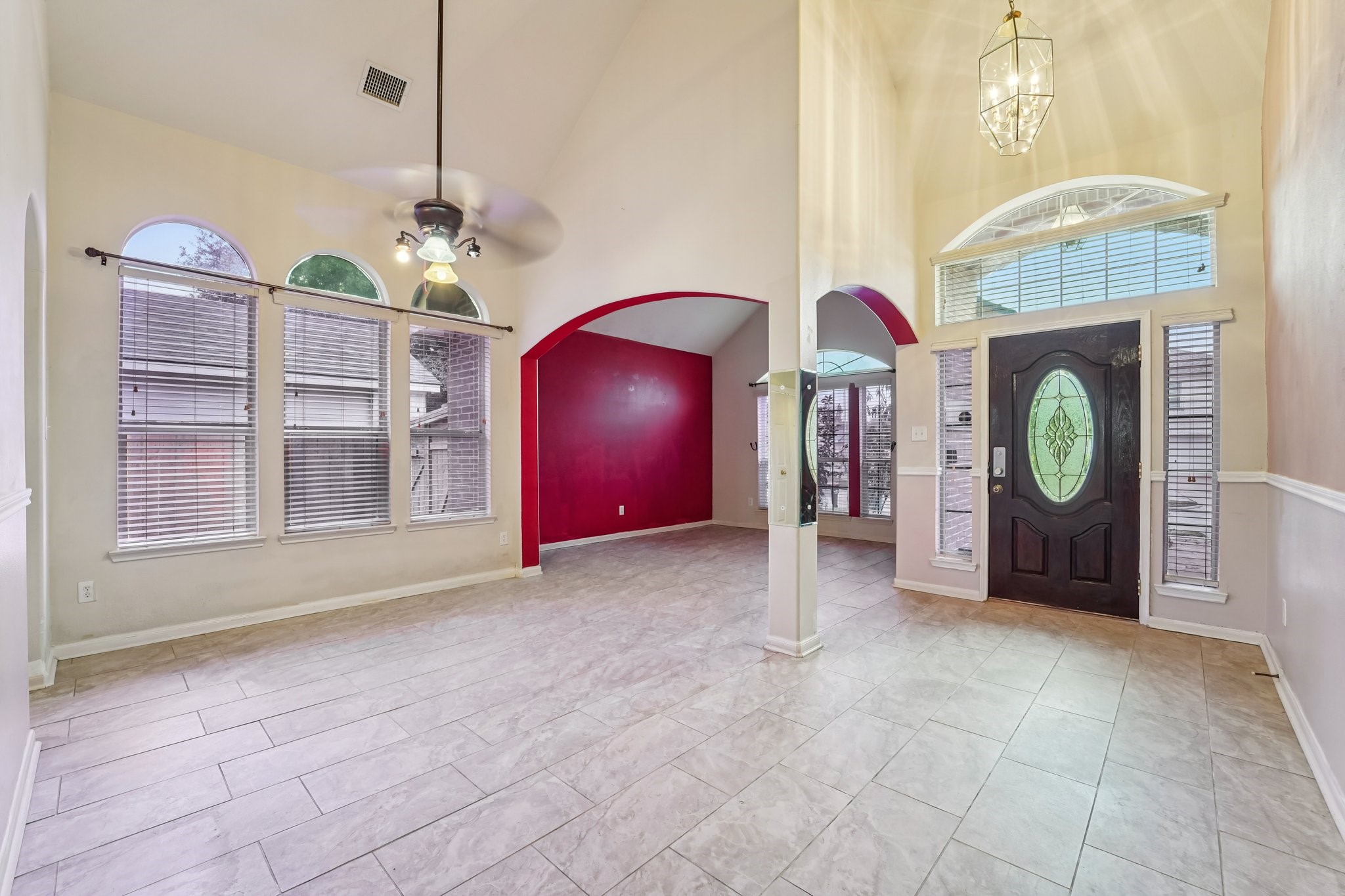 3818 Ridge Canyon Road Baytown, TX 77521 - Photo 7 of 42 This spacious entryway features high ceilings, large windows with abundant natural light, elegant tile flooring, and a stylish front door. The open layout includes a bold accent wall, enhancing the inviting atmosphere.