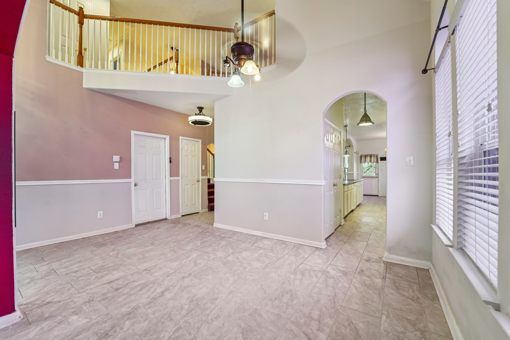 3818 Ridge Canyon Road Baytown, TX 77521 - Photo 8 of 42 This home features a bright, open living space with high ceilings and a second-floor balcony. The tile flooring complements the soft wall colors, and large windows provide ample natural light. An arched entryway leads to the kitchen, offering a seamless flow for entertaining.