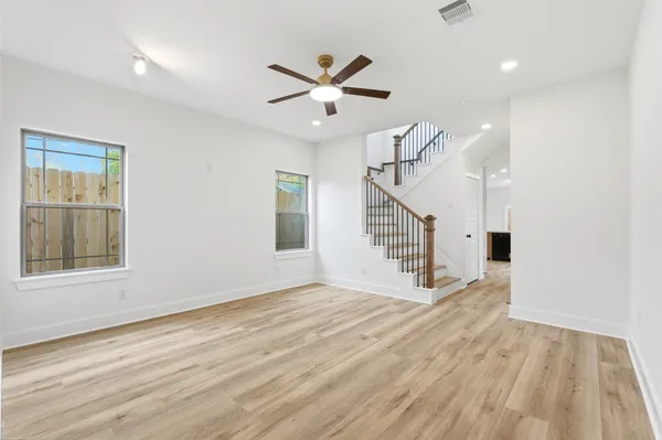 a view of empty room with wooden floor and fan