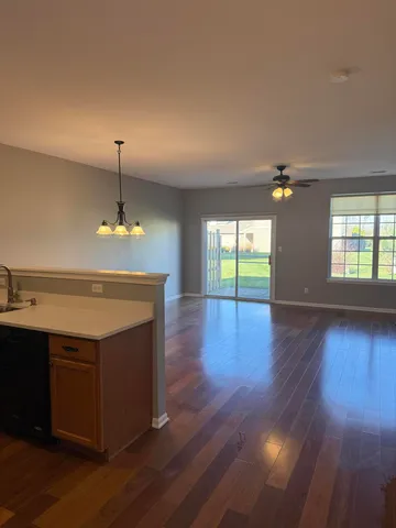 a view of a room with wooden floor and kitchen view