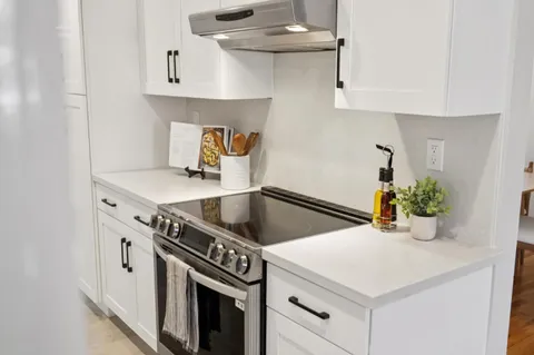 a kitchen with stainless steel appliances a white cabinets and wooden floor