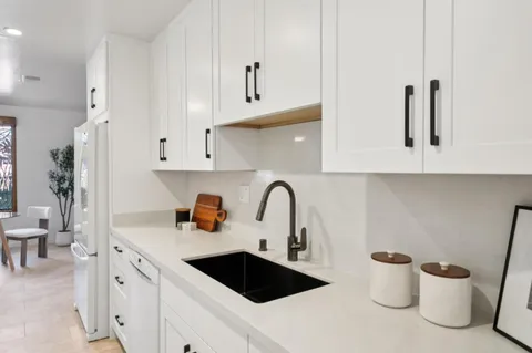 a kitchen with a sink and a stove with white cabinets
