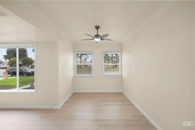 an empty room with windows and chandelier fan