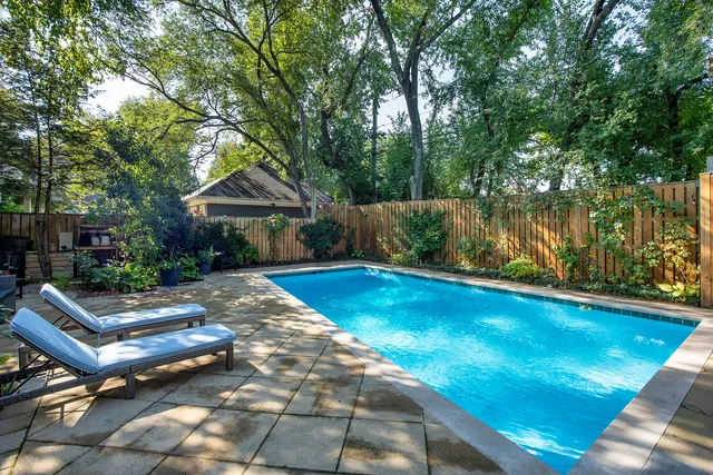 a view of swimming pool with lawn chairs and wooden fence