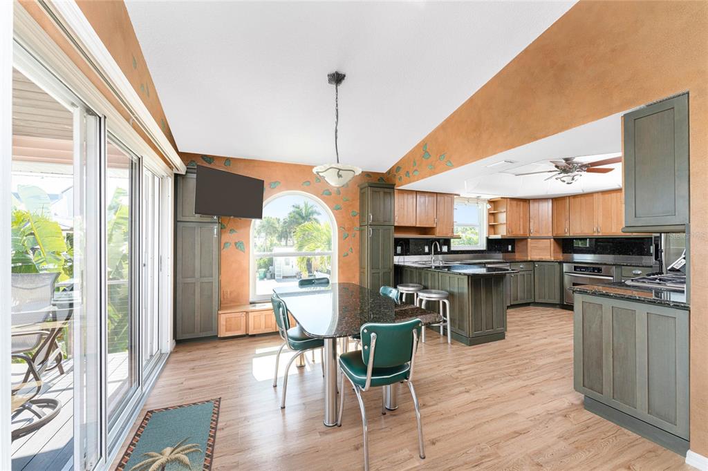 2805 North Beach Road, Unit B Englewood, FL 34223 - Photo 13 of 86 a kitchen with stainless steel appliances granite countertop a stove top oven a sink dishwasher a dining table and chairs with wooden floor