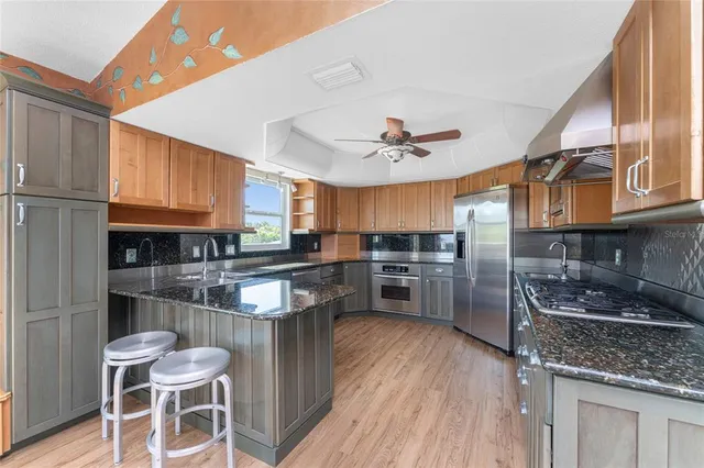 a kitchen with stainless steel appliances granite countertop a sink a stove and a refrigerator