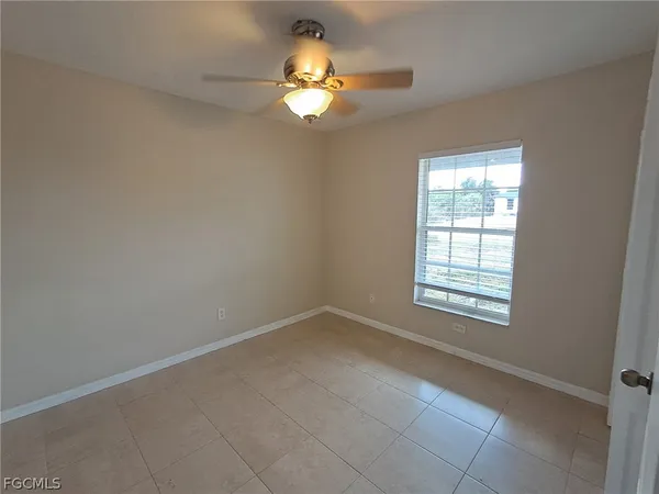 an empty room with a chandelier fan and windows