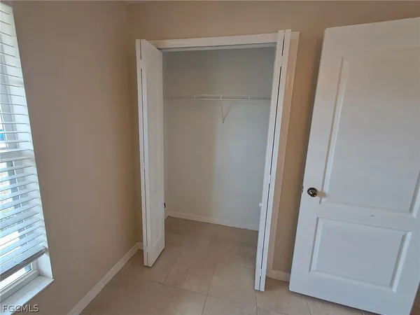 an empty room with a chandelier fan and windows