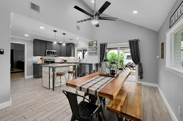 a kitchen with stainless steel appliances a dining table chairs and wooden floor