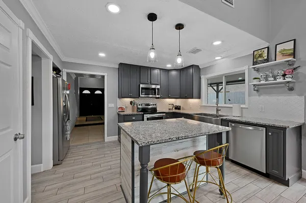 a kitchen with stainless steel appliances granite countertop a table chairs sink and microwave
