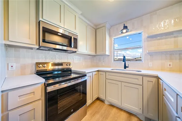 a kitchen with white cabinets and stainless steel appliances