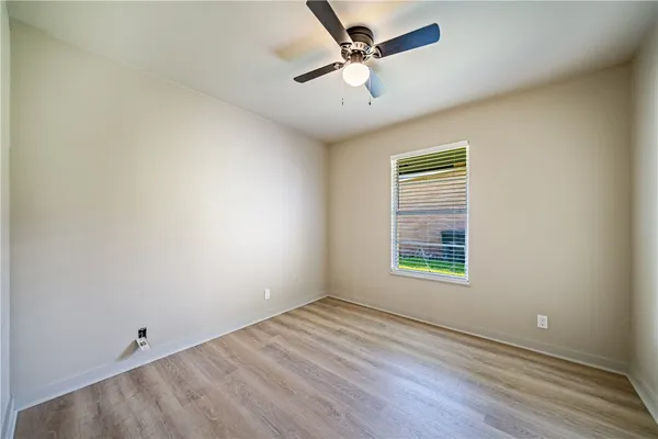 an empty room with a window and a ceiling fan
