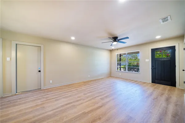 a view of an empty room with wooden floor and a window