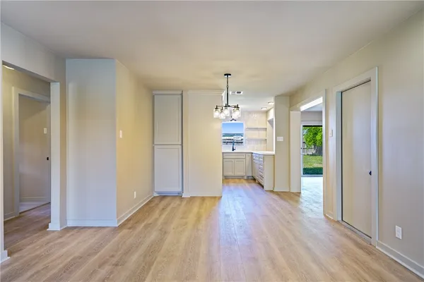 a view of a kitchen with wooden floor a refrigerator and a window