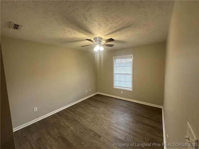 an empty room with wooden floor closet and windows